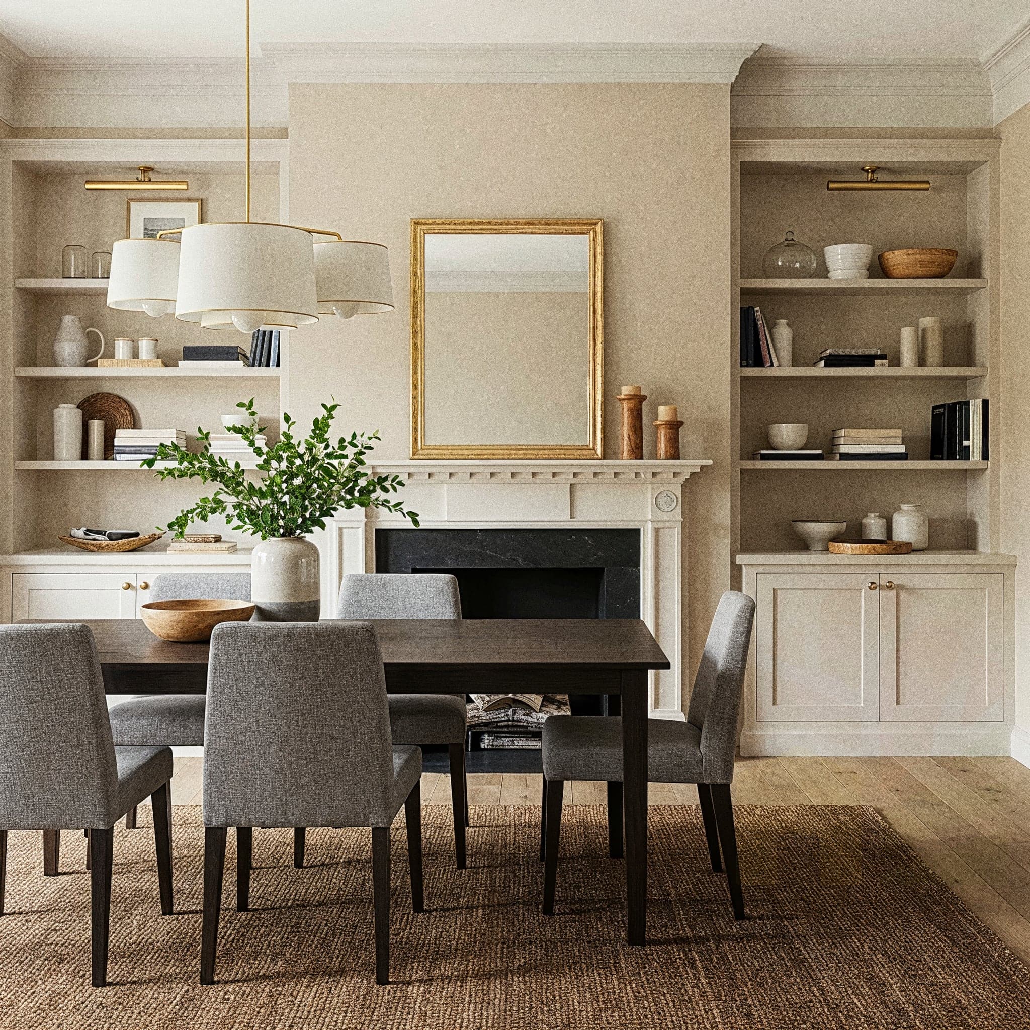 A striking dining room with an Industrial Chic design, featuring a rugged wooden dining table with black metal legs, surrounded by mismatched metal and wood chairs with leather seats. The room includes a pendant light with exposed Edison bulbs, a metal-framed shelf with potted succulents and vintage decor, and a concrete-textured wall. Large windows with sheer curtains allow natural light to highlight the dark wooden floor and metallic accents, creating a bold yet inviting atmosphere.